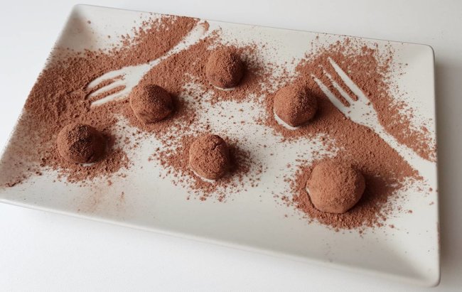 Čokoladne energetske okruglice na tanjuru posipane kakao prahom.